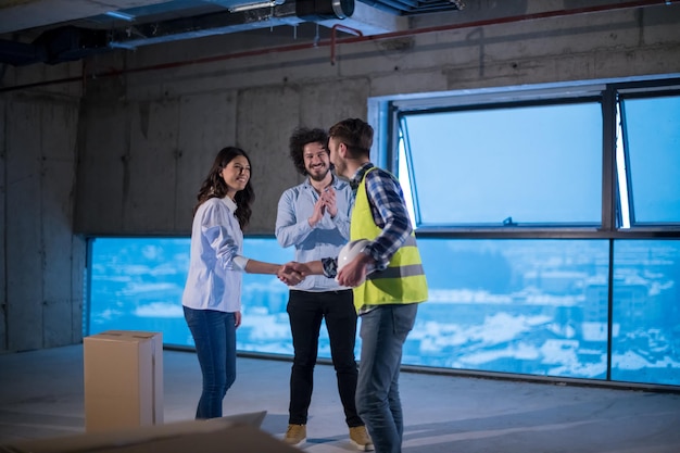 equipo joven de empresarios en grupo, arquitecto e ingeniero en el sitio de construcción revisando documentos y flujo de trabajo de negocios usando una computadora portátil en una nueva oficina de inicio