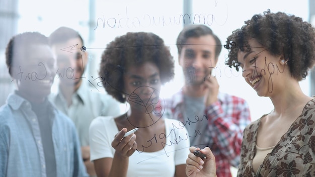 Foto un equipo de jóvenes diseñadores pegando notas en el vidrio en una oficina moderna