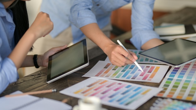 equipo de jóvenes diseñadores profesionales que usa una tableta digital mientras elige el color en una muestra de color