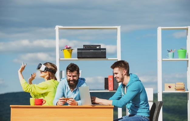 Equipo de jóvenes empresarios que usan auriculares vr trabajando con un nuevo proyecto virtual en exteriores modernos