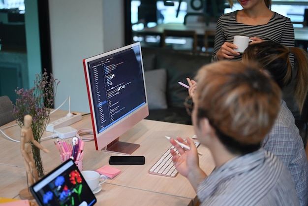 Equipo de jóvenes programadores y desarrolladores de software de TI discutiendo y trabajando juntos en un proyecto de sitio web en la oficina