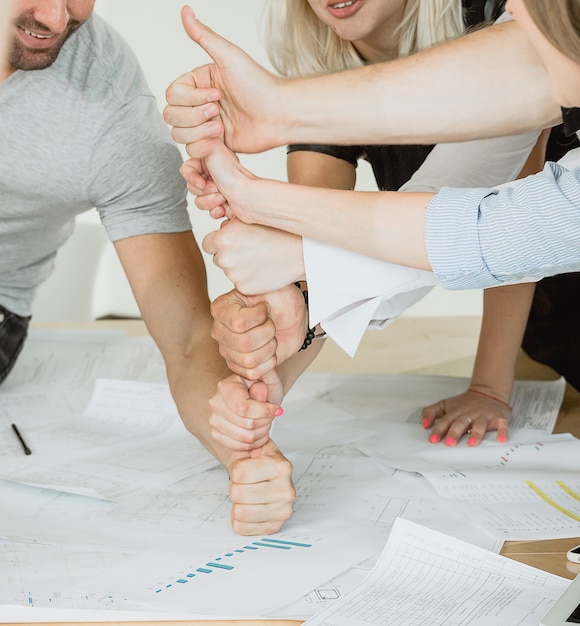 Equipo de jóvenes que trabajan con diagramas en la mesa.