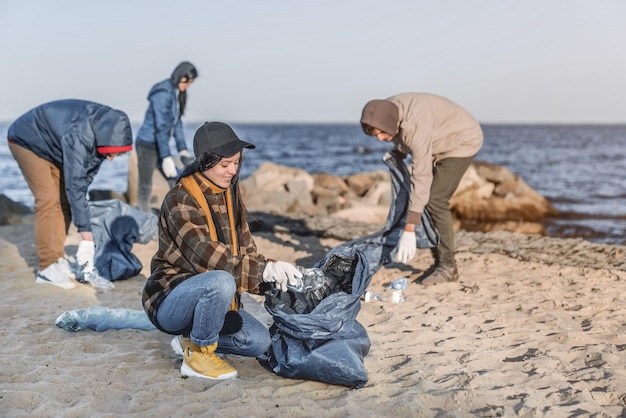 Equipo de jóvenes voluntarios está recogiendo plástico en una playa