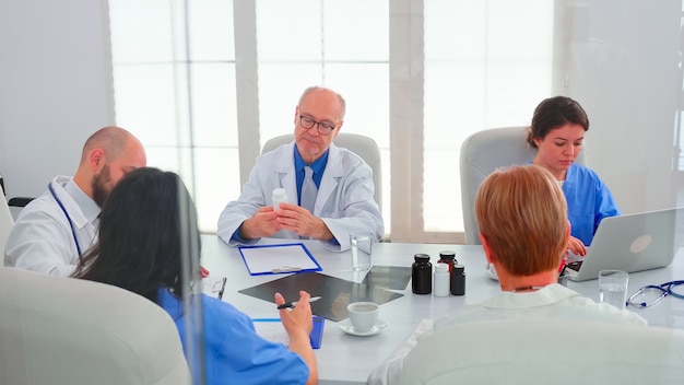 Equipo médico concentrado discutiendo la búsqueda de soluciones juntos en la sala de reuniones del hospital. Terapeuta experto de la clínica hablando con colegas sobre la enfermedad, profesional de la medicina