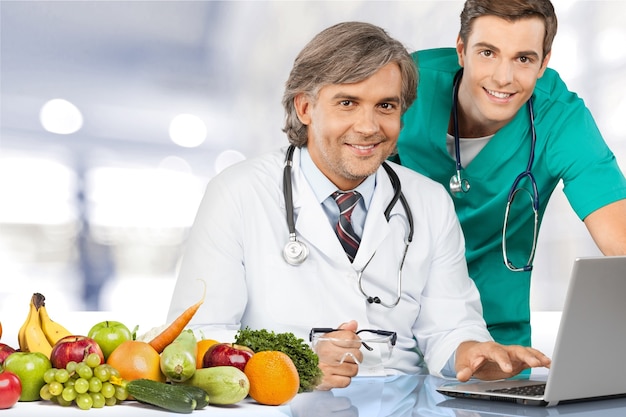 Equipo médico confiado en el hospital con laptop y frutis