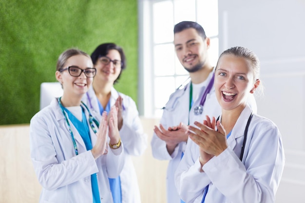 Equipo médico feliz compuesto por médicos masculinos y femeninos sonriendo ampliamente y dando un pulgar hacia arriba del éxito y la esperanza
