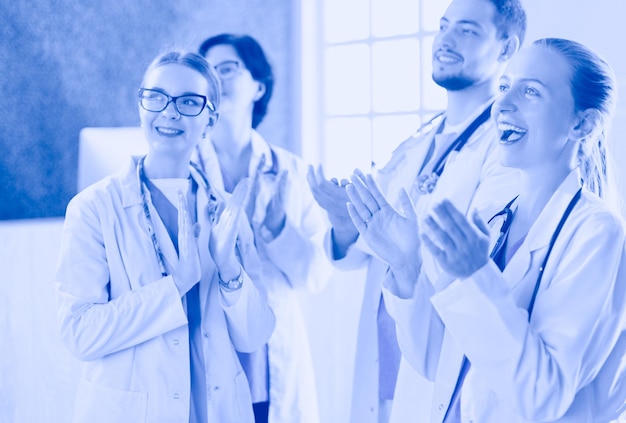 Equipo médico feliz compuesto por médicos masculinos y femeninos sonriendo ampliamente y dando un pulgar hacia arriba del éxito y la esperanza