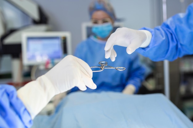 El equipo médico de médicos y enfermeras está realizando una operación quirúrgica en la sala de emergencias del asistente del hospital entrega tijeras e instrumentos a los cirujanos durante la operación