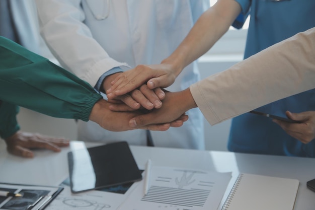 Equipo médico multirracial que tiene una reunión con médicos con batas blancas de laboratorio y batas quirúrgicas sentados en una mesa discutiendo los registros de los pacientes