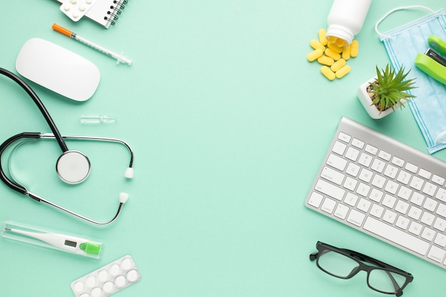 Foto equipo médico y portátil con planta suculenta sobre fondo verde pastel