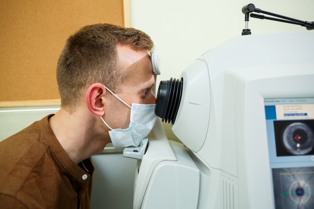 Foto equipo médico profesional escaneando los ojos del paciente. el dispositivo de una clínica de salud moderna.