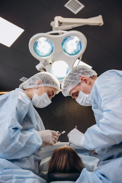 Equipo médico profesional que realiza una operación quirúrgica en un quirófano moderno El asistente asiático entrega instrumentos al médico cirujano durante la operación en un paciente de cuidados intensivos en el hospital