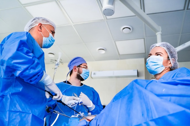 Equipo médico que ayuda al cirujano del paciente con su equipo a realizar una cirugía en una sala de operaciones del paciente