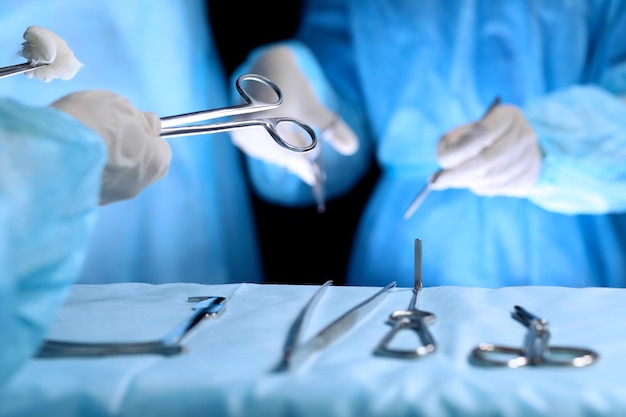 Equipo médico realizando la operación. Grupo de cirujanos está trabajando en quirófano en tonos azules.