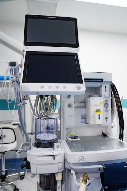 Equipo médico en la sala de operaciones Un ventilador médico con una pantalla y varias mangueras y tubos está en una sala de operaciones del hospital