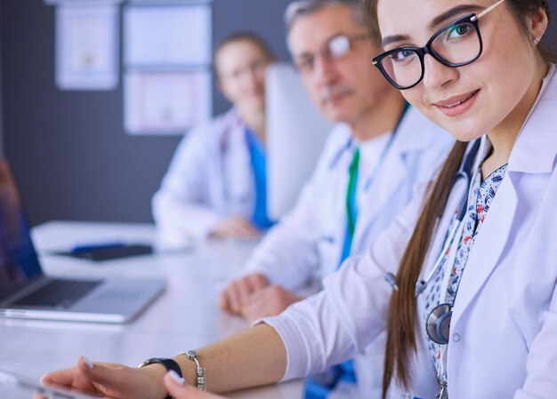 Foto equipo médico serio usando una computadora portátil en una oficina luminosa