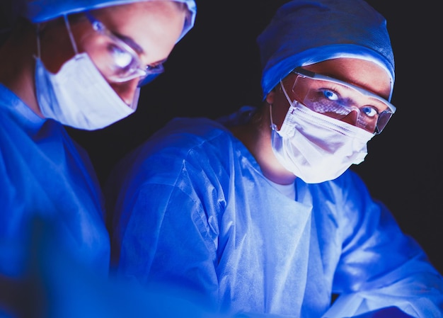 Equipo de médicos en cirugía en un fondo oscuro