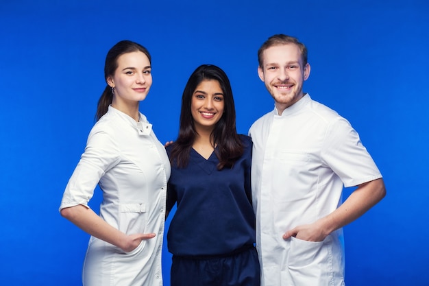 Foto un equipo de médicos jóvenes. gente multinacional - médico, enfermera y cirujano en fondo azul. un grupo de estudiantes de medicina de diferentes nacionalidades está mirando en la celda.