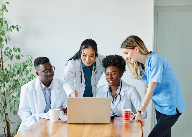 Equipo de médicos que trabajan en la computadora portátil que muestra unidad entre ellos