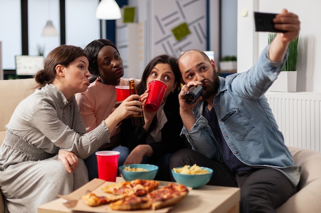 Equipo multiétnico de amigos crea recuerdos en la fiesta después del trabajo