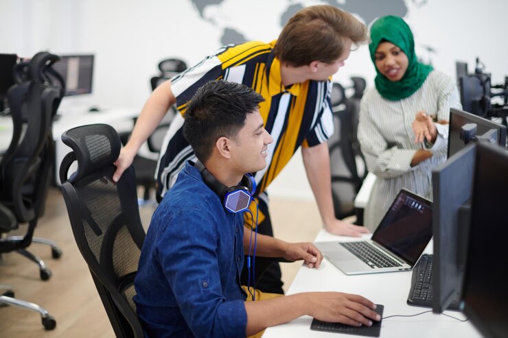 Foto equipo multiétnico de empresas emergentes mujer árabe que usa un hiyab en una reunión en una moderna oficina abierta con lluvia de ideas en el interior, trabajando en una computadora portátil y una computadora de escritorio