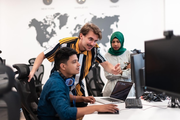 Equipo multiétnico de empresas emergentes Mujer árabe que usa un hiyab en una reunión en una moderna oficina abierta con lluvia de ideas en el interior, trabajando en computadoras portátiles y de escritorio. Enfoque selectivo. foto de alta calidad