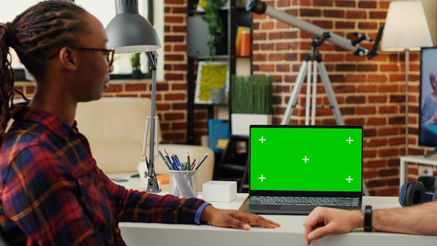 Equipo multiétnico de hombres y mujeres que analizan la pantalla verde en una laptop, usando una plantilla de clave de croma en blanco en una PC inalámbrica. Haciendo colaboración de trabajo en equipo con copyspace de maqueta aislado.