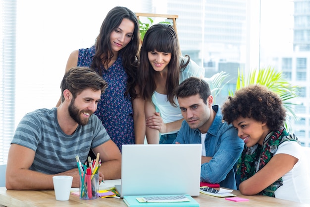 Equipo de negocio creativo feliz reunidos alrededor de una computadora portátil