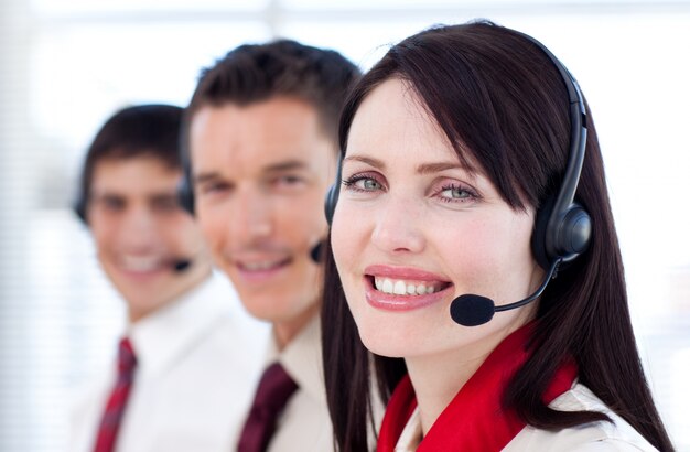 Equipo de negocios con auriculares sonriendo a la cámara