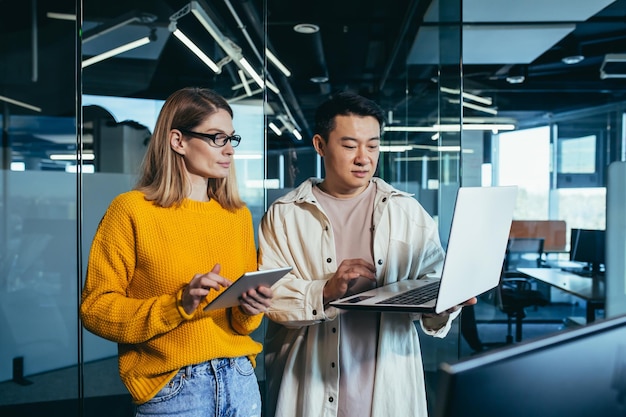 El equipo de negocios de Brainstrom es responsable de resolver las tareas, los empleados, los colegas, el hombre y la mujer asiáticos, trabajan juntos en una oficina moderna.