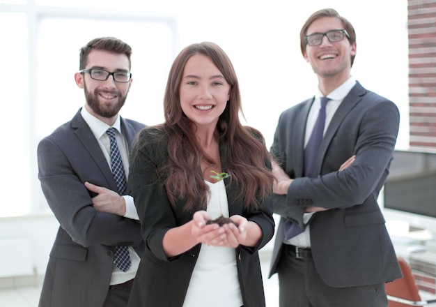 Equipo de negocios con un brote joven mirando a la cámara.