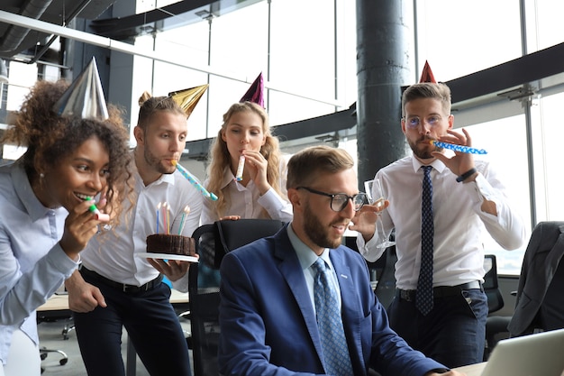 Equipo de negocios celebrando el cumpleaños de un colega en la oficina moderna.