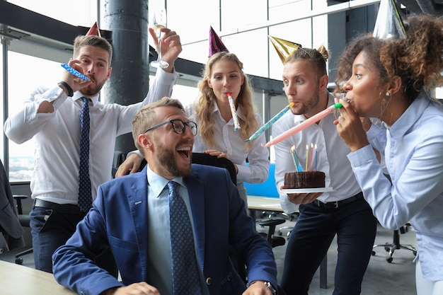 Equipo de negocios celebrando el cumpleaños de un colega en la oficina moderna.