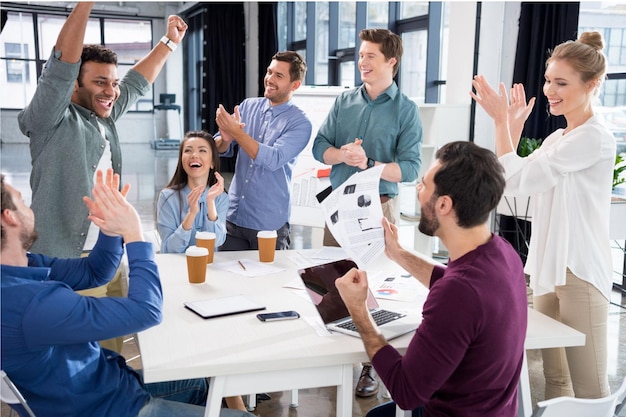 Equipo de negocios celebrando el éxito juntos en el lugar de trabajo en la oficina concepto de grupo profesional joven