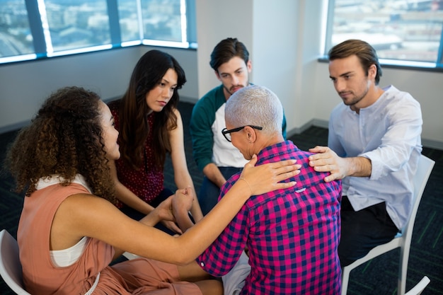 Equipo de negocios creativos consolando a un colega molesto en la oficina