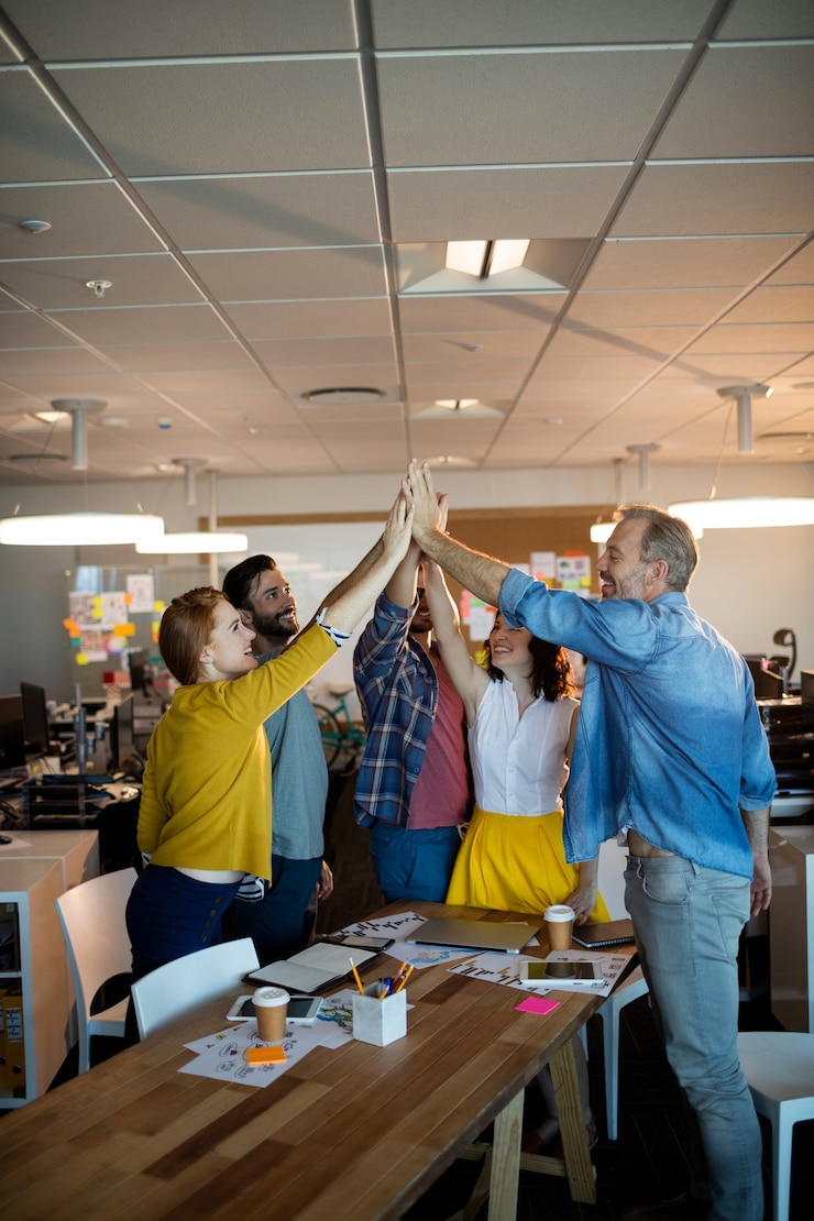 Equipo de negocios creativos dando un alto cinco el uno al otro en la oficina