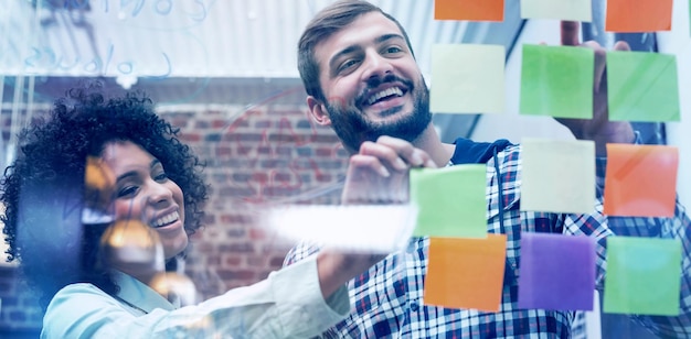 Equipo de negocios creativos mirando notas adhesivas en la ventana