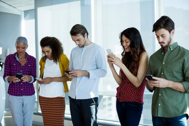 Equipo de negocios creativos sonriente mediante teléfono móvil en la oficina