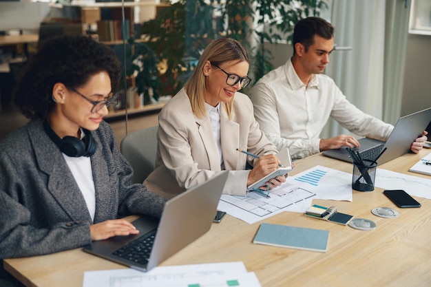 El equipo de negocios está analizando un nuevo proyecto financiero mientras trabajan juntos en el escritorio de la oficina