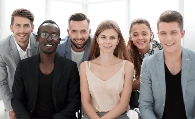 Equipo de negocios exitoso y seguro de diversos ejecutivos posando juntos en una oficina sonriendo alegremente a la cámara