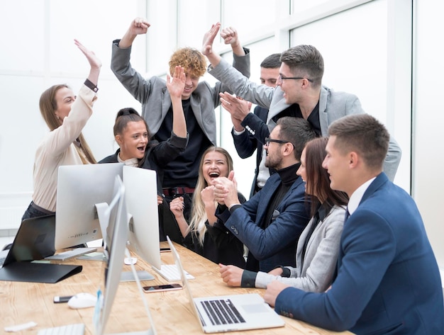 Equipo de negocios exultante mirando la pantalla de la computadora de la oficina