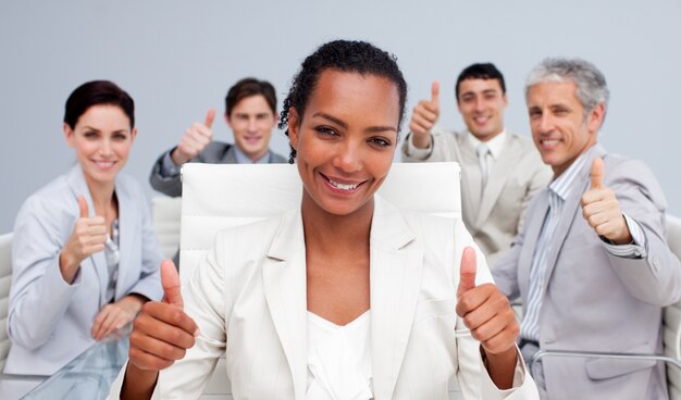 Equipo de negocios feliz celebrando un éxito con los pulgares arriba