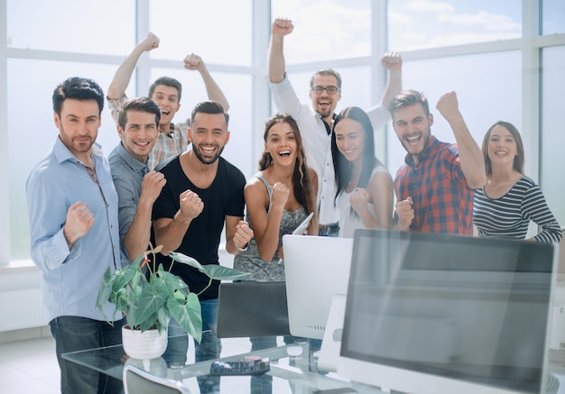 Foto equipo de negocios feliz de pie en la oficina moderna el concepto de una puesta en marcha