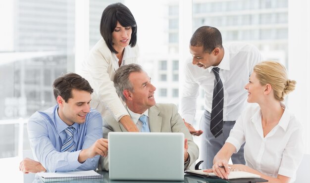 Equipo de negocios feliz se reunieron alrededor de hablar portátil