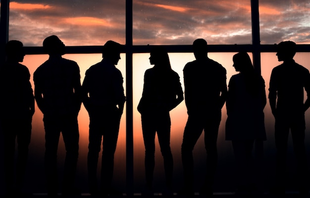 Foto equipo de negocios hablando de pie cerca de una ventana grande