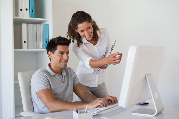 Equipo de negocios informal mirando la computadora juntos en el escritorio