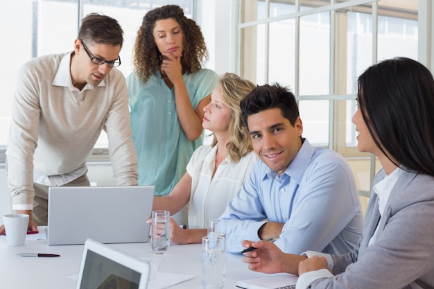 Equipo de negocios informal que tiene una reunión usando la computadora portátil