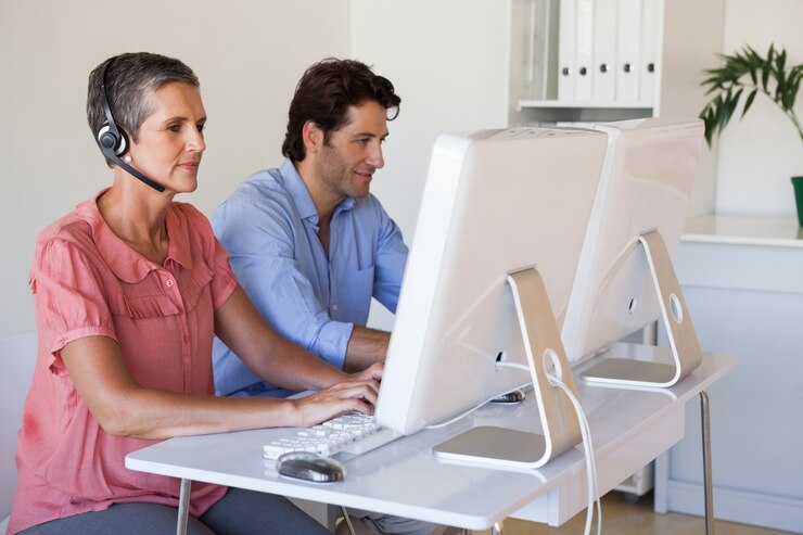 Foto equipo de negocios informal trabajando en el escritorio usando computadoras con mujer usando auriculares