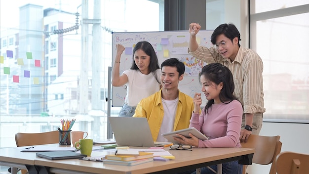 Equipo de negocios de inicio celebrando la victoria corporativa juntos en la oficina