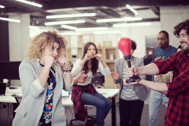 Equipo de negocios de inicio multiétnico de desarrolladores de software divirtiéndose mientras boxean en la oficina, empleados diversos emocionados riendo disfrutando de actividades divertidas en el descanso del trabajo, trabajadores creativos y amigables jugando